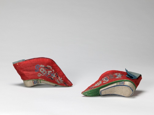 Red satin shoes with intricately embroidered bats, Chinese symbols, and serpentine shapes in light blue-shaded thread.