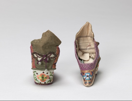 Embroidered flowers and gold sequins surround a scrolling vine on a pair of pastel pink shoes with pastel green heels. The shoes have a small white bead on the toes and a butterfly on the backs.
