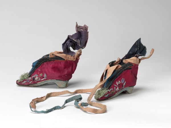 A magenta pair of shoes embroidered with light blue, green, pink, and yellow birds, butterflies, and lotus flowers.