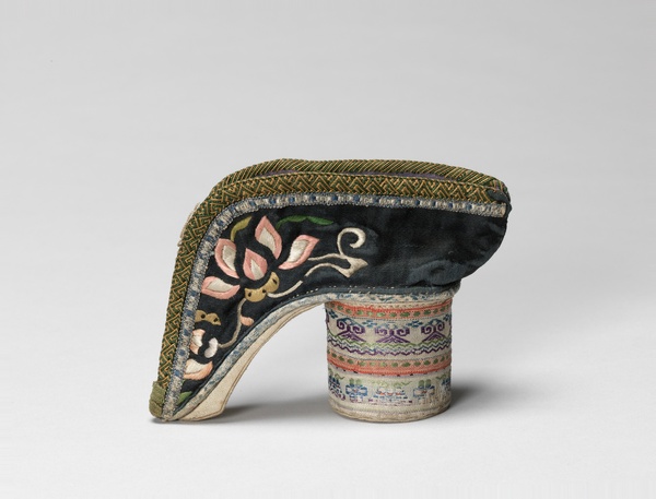 A tall and cylindrically heeled shoe with pink lotus blossoms embroidered on top of black silk.